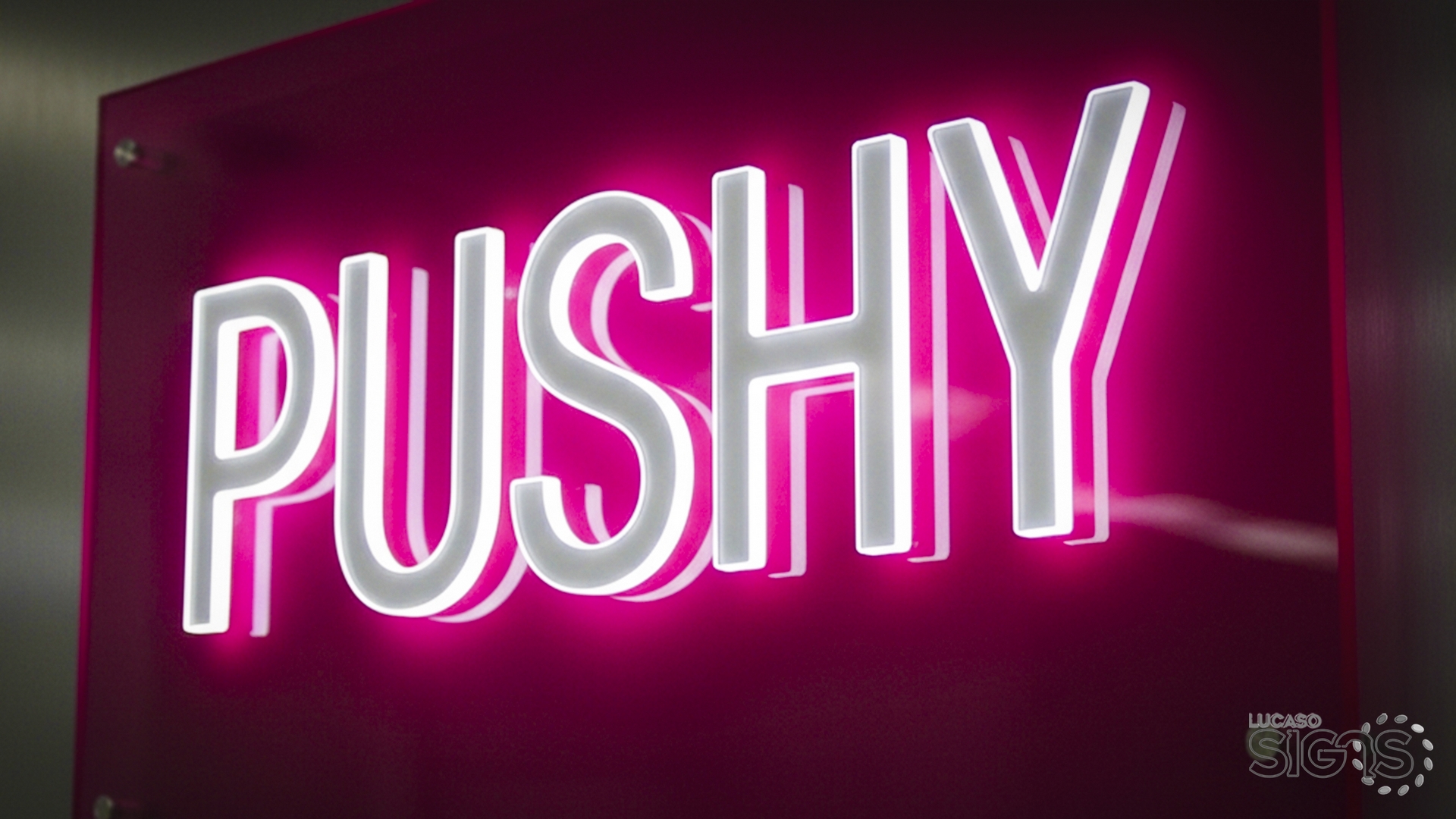Custom push-through illuminated sign with white glowing letters on a magenta background spelling PUSHY by Lucaso Signs